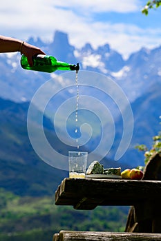 Pouring from high height of natural Asturian cider made fromÂ fermented apples, Asturian cabrales cow blue cheese with view on